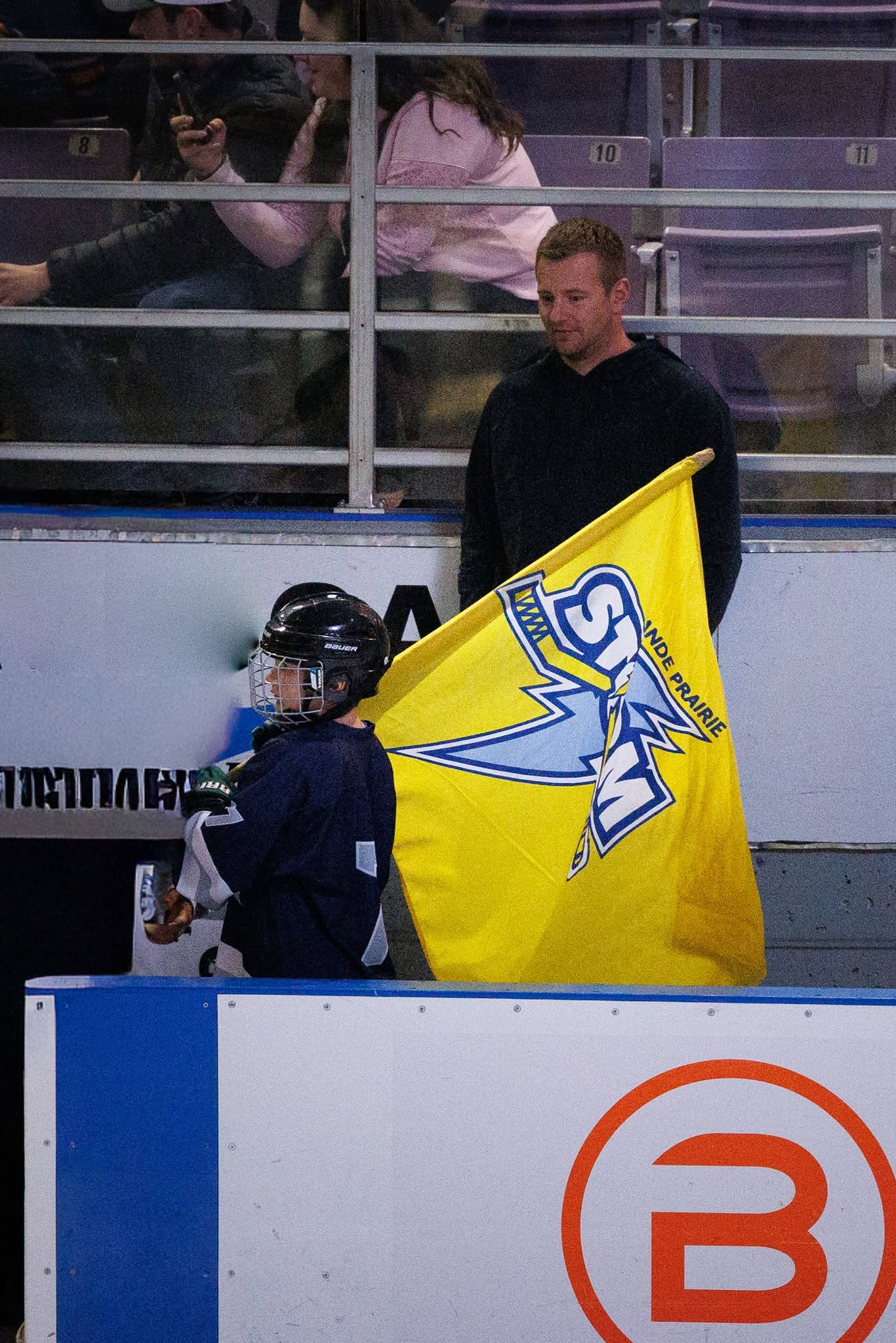 A young player carrying the Grande Prairie Storm flag onto the ice