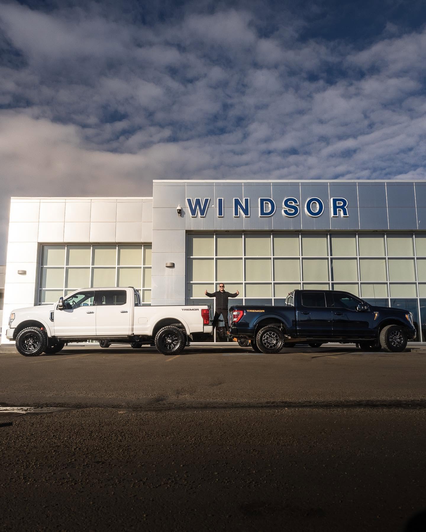 A team member between two Ford Tremor trucks in front of the dealership