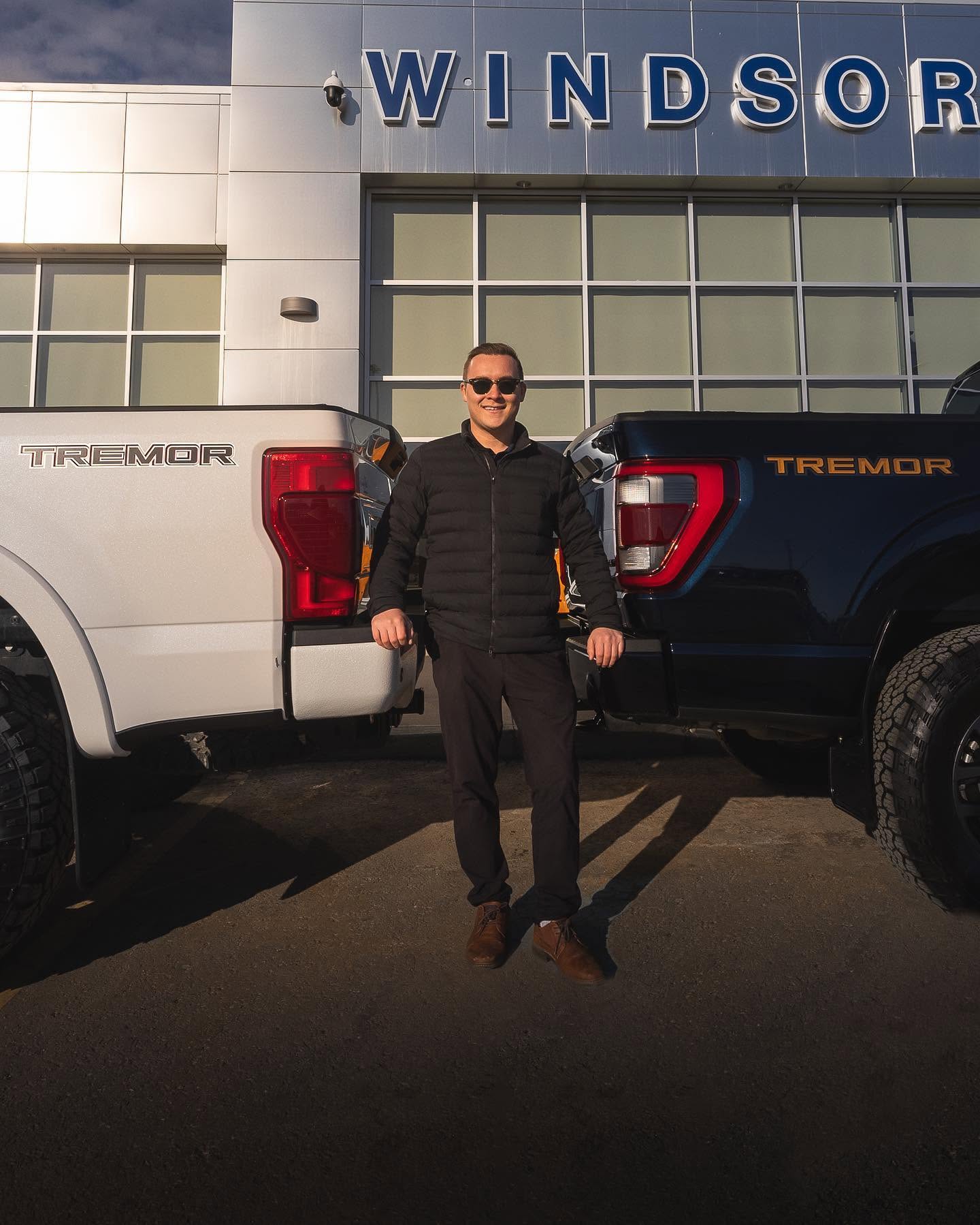 A Windsor Ford sales team member between two Ford Tremor trucks at the dealership