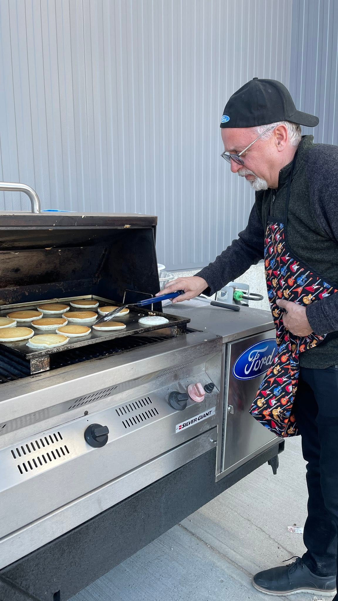A Windsor Ford team member flipping pancakes on a Ford grill
