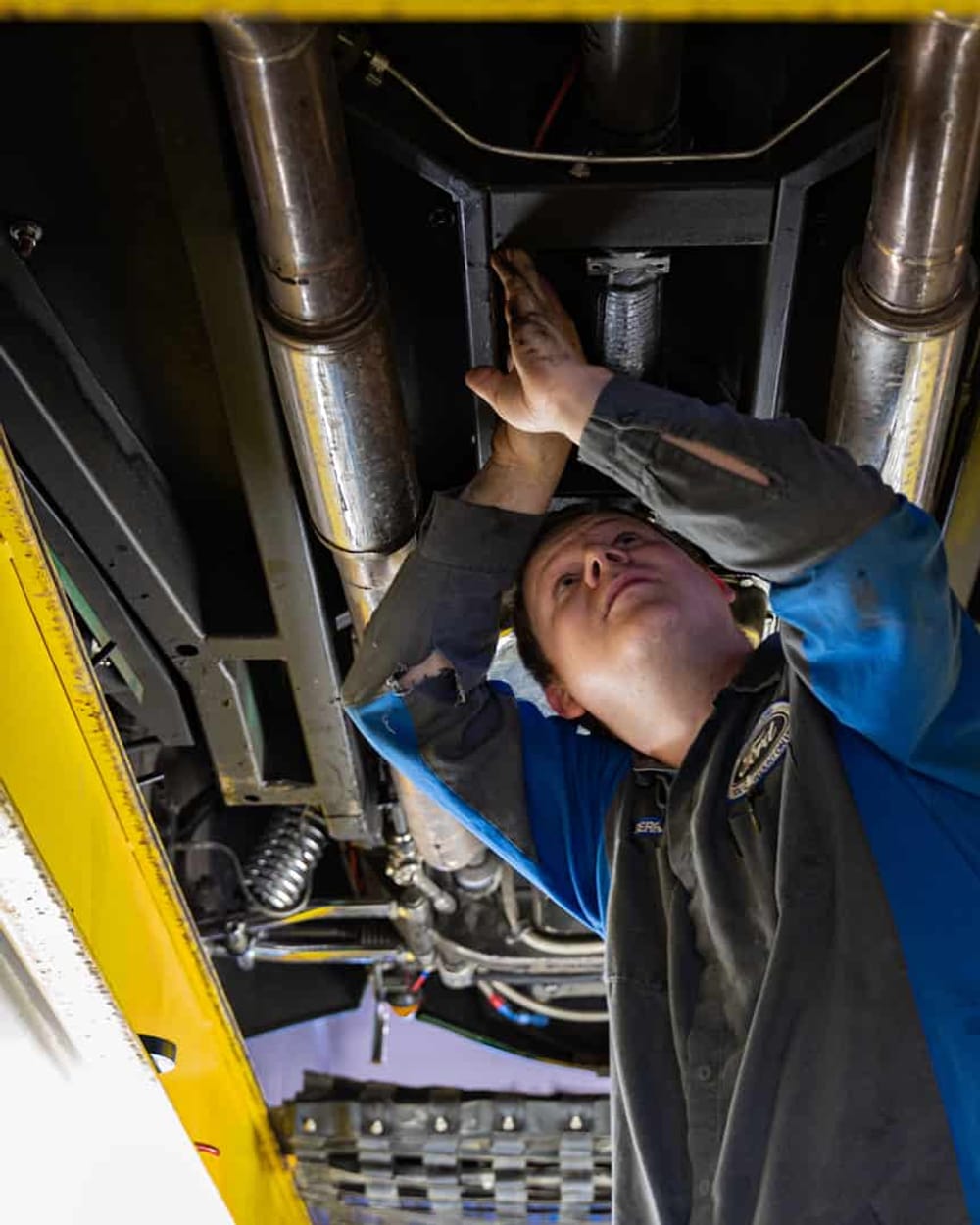 Ford-badged technician working underneath a vehicle on a hoist at Windsor Ford