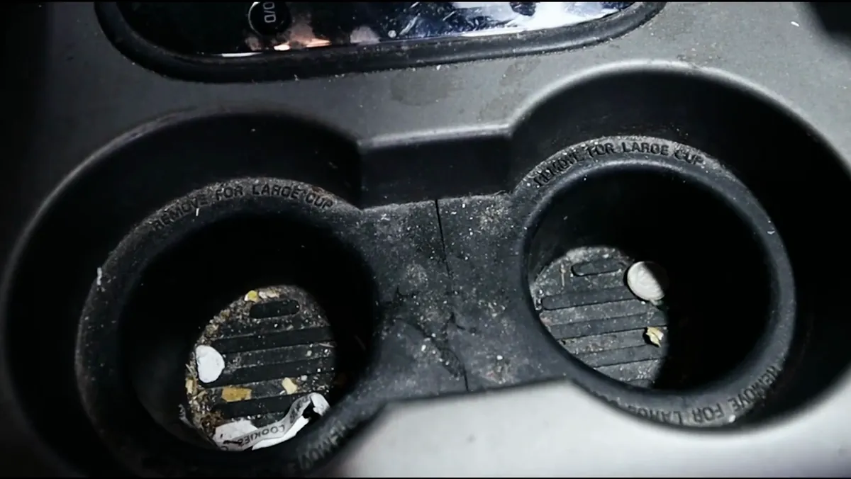 Grimy cup holders full of debris in a Ford F-150 before detailing